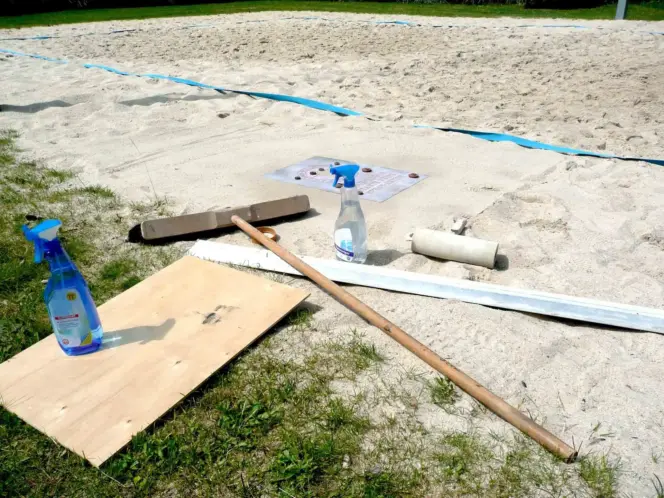 Werkzeuge im Sand: Besen, Rolle, Sprühflasche