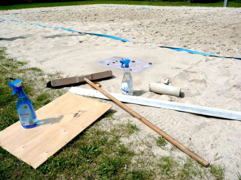 Werkzeuge im Sand: Besen, Rolle, Sprühflasche